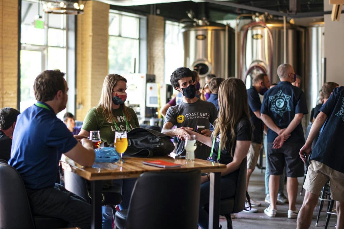 Group with health masks conversing while sitting at a table with drinks