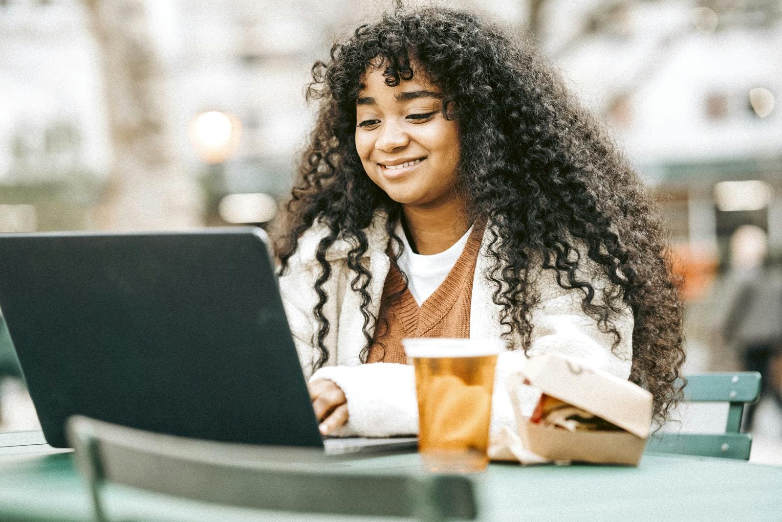 Woman using laptop in a cafe with a coffee cup besides the laptop
